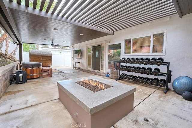 view of patio featuring fence, a hot tub, a pergola, and an outdoor fire pit