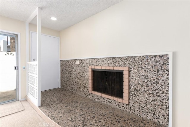 interior details featuring a fireplace, a textured ceiling, and carpet