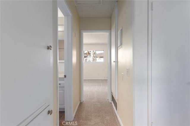 hallway featuring light carpet, baseboards, and visible vents