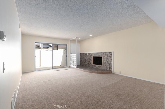 unfurnished living room featuring a fireplace, carpet floors, a textured ceiling, and visible vents