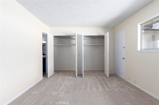 unfurnished bedroom with multiple closets, a textured ceiling, and carpet flooring