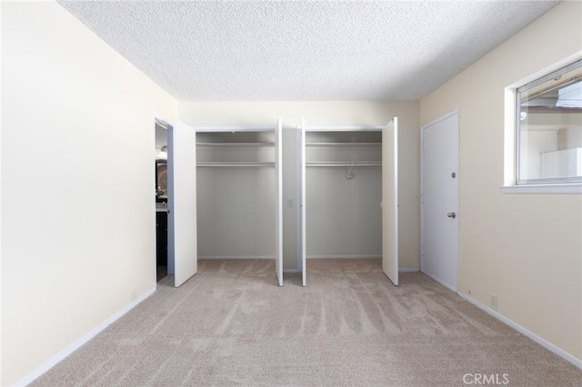 unfurnished bedroom featuring multiple closets, carpet flooring, and a textured ceiling