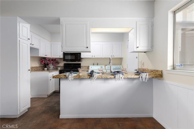 kitchen with a peninsula, light stone counters, white cabinetry, and black appliances