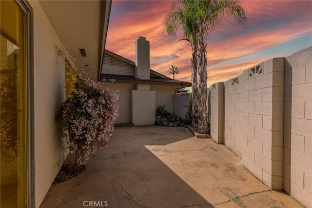 patio terrace at dusk featuring fence
