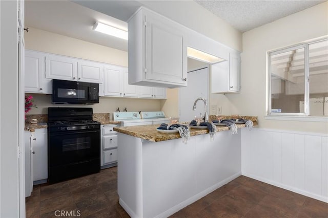 kitchen with black appliances, washer and clothes dryer, a wainscoted wall, white cabinets, and a textured ceiling