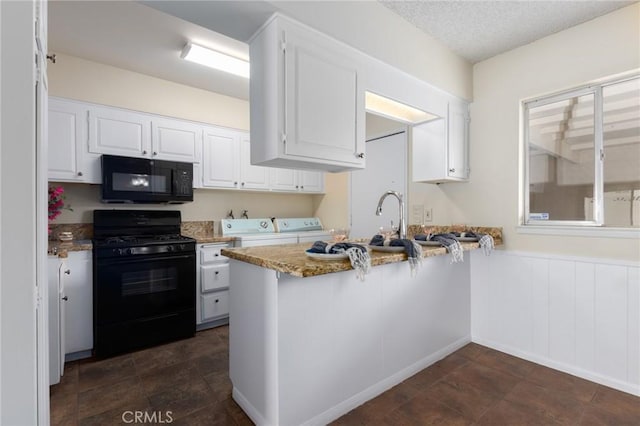 kitchen with white cabinets, washing machine and clothes dryer, wainscoting, a peninsula, and black appliances