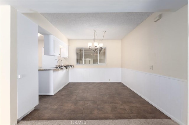 unfurnished dining area with wainscoting and a chandelier