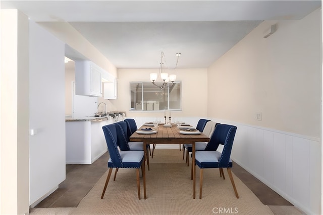 dining space featuring an inviting chandelier and a wainscoted wall