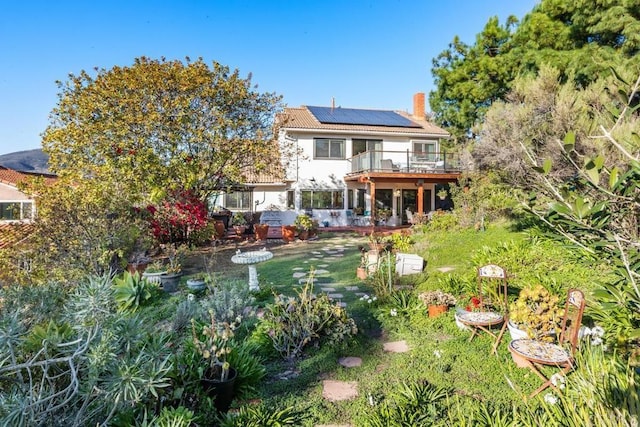 back of property featuring solar panels, a chimney, and a wooden deck