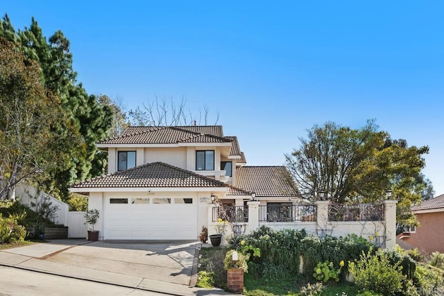 view of front facade featuring fence, a tile roof, stucco siding, a garage, and driveway