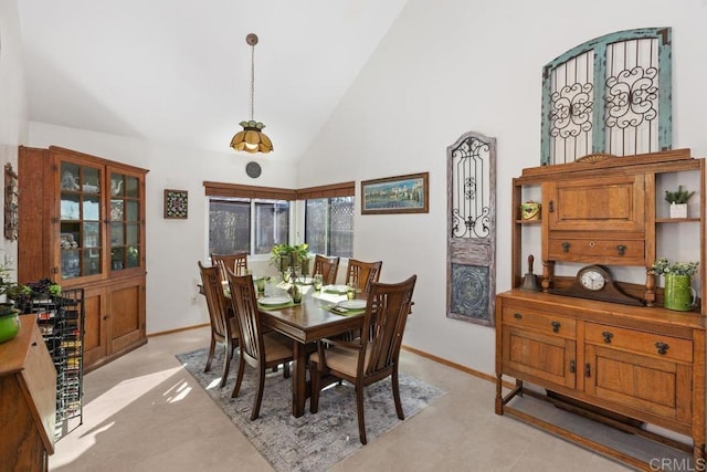 dining area featuring high vaulted ceiling and baseboards