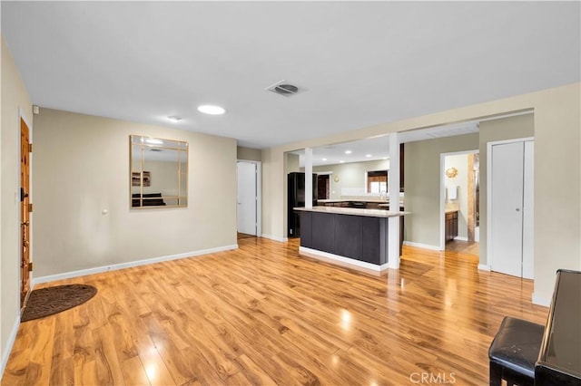 unfurnished living room featuring light wood-type flooring, visible vents, and baseboards