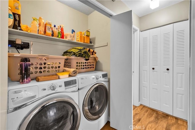 clothes washing area with laundry area, washing machine and dryer, and light wood finished floors