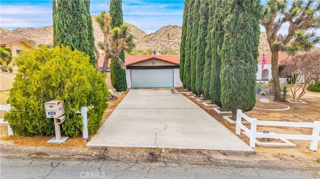 obstructed view of property with concrete driveway, fence, and a mountain view