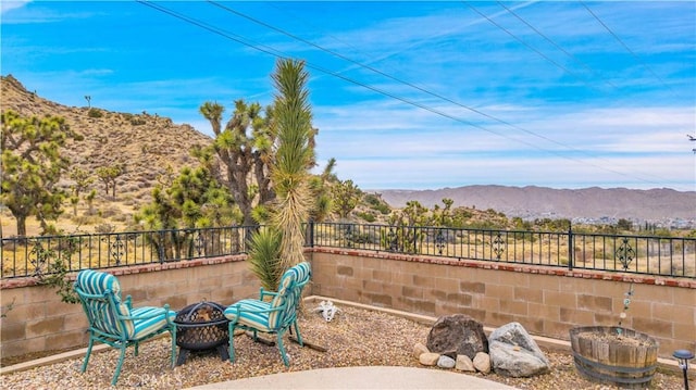 view of patio / terrace with a mountain view, a fire pit, and a fenced backyard