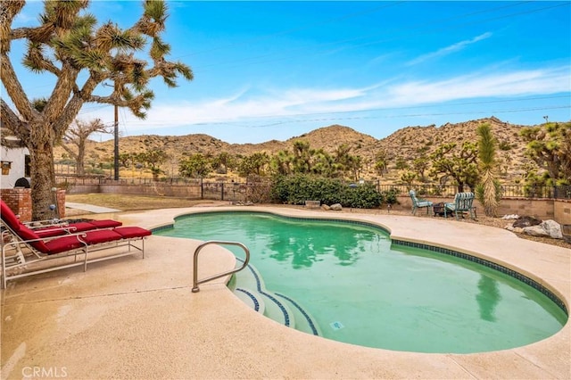 view of pool with a patio, a fenced in pool, fence, and a mountain view