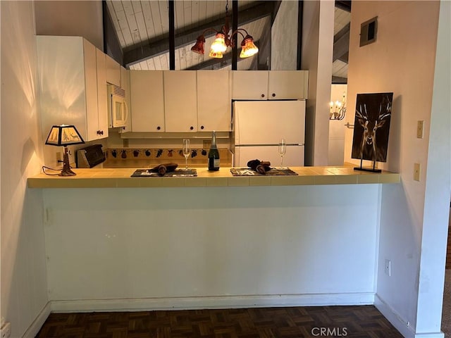 kitchen with visible vents, tile counters, lofted ceiling with beams, a peninsula, and white appliances