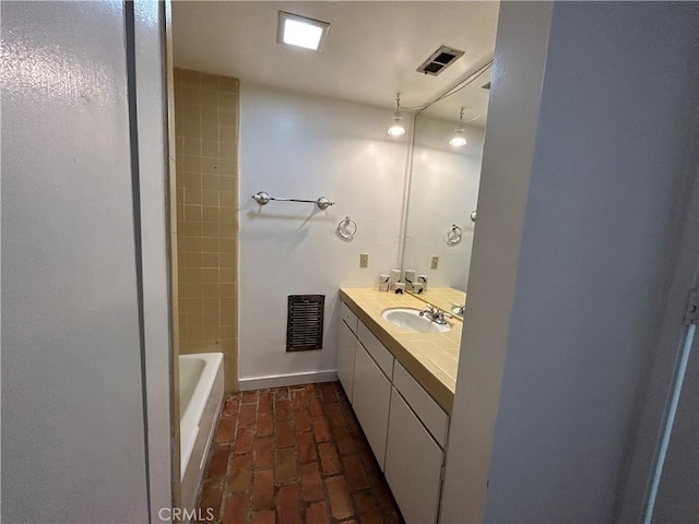 full bath with visible vents, vanity, and brick floor