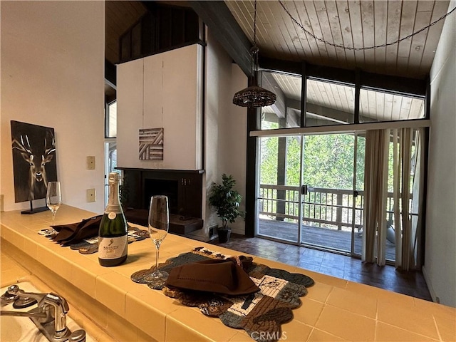 kitchen with tile counters, beamed ceiling, wooden ceiling, a fireplace, and high vaulted ceiling