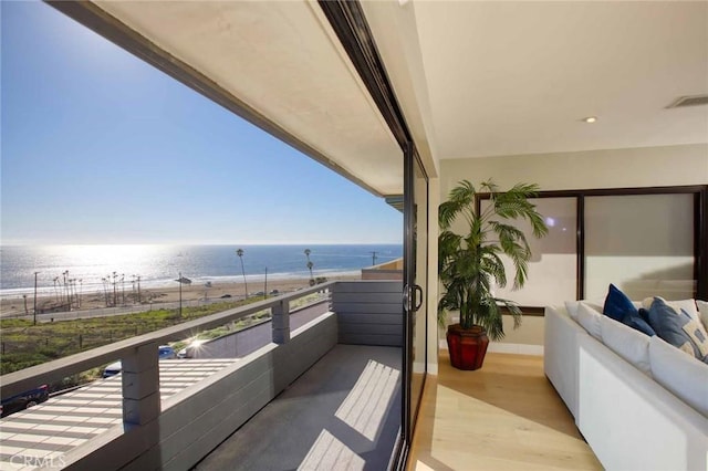 balcony featuring visible vents, a water view, and a beach view