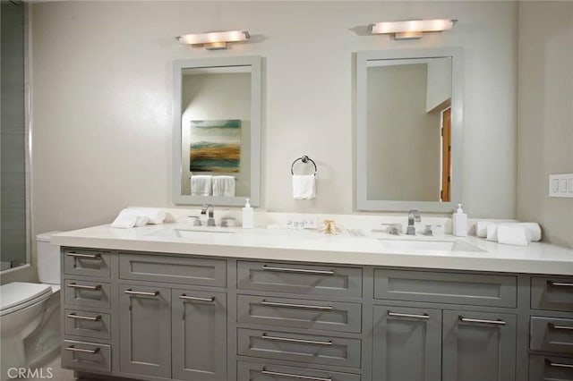 full bath with double vanity, toilet, and a sink