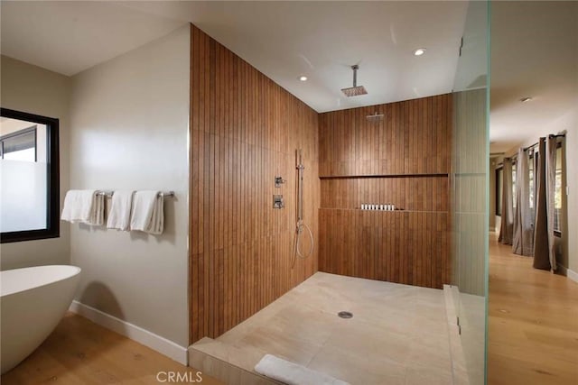 bathroom with a freestanding tub, tiled shower, and wood finished floors