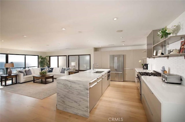 kitchen featuring light wood-type flooring, modern cabinets, a sink, tasteful backsplash, and stainless steel appliances