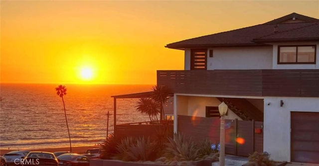 exterior space featuring stucco siding, a balcony, and a water view