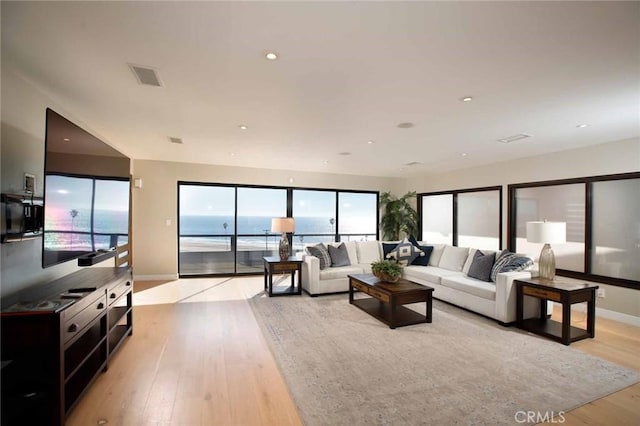 living area featuring baseboards, recessed lighting, visible vents, and light wood-type flooring