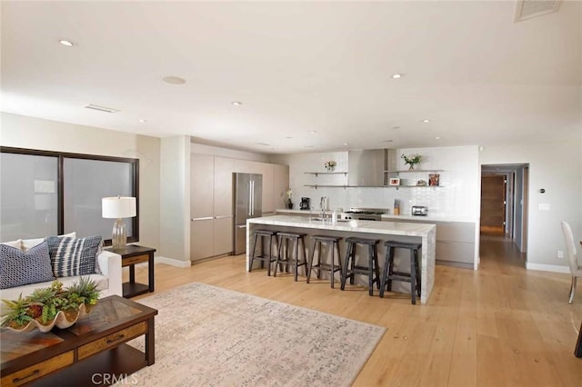 living area with recessed lighting, visible vents, baseboards, and light wood finished floors