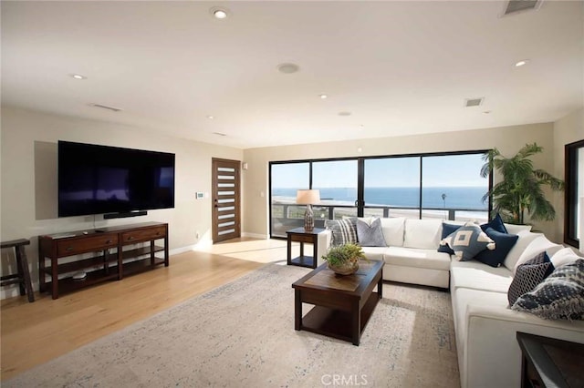 living area featuring visible vents, baseboards, a water view, light wood-type flooring, and recessed lighting