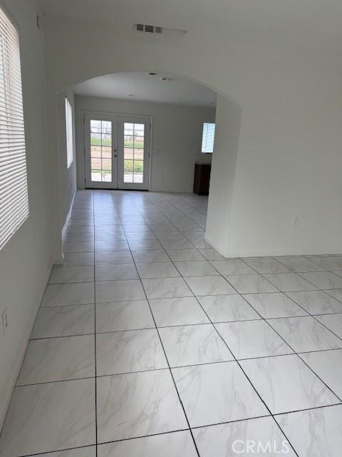 spare room featuring visible vents, arched walkways, and french doors