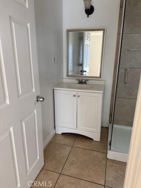 bathroom with tile patterned flooring, a stall shower, vanity, and baseboards