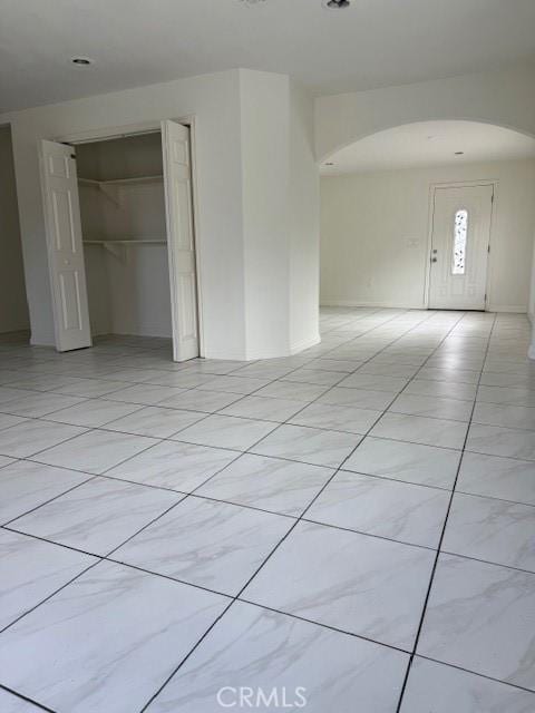 spare room featuring arched walkways and light tile patterned floors