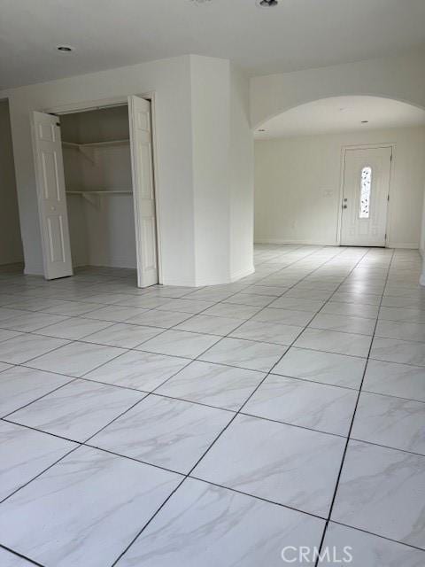 empty room featuring light tile patterned floors and arched walkways