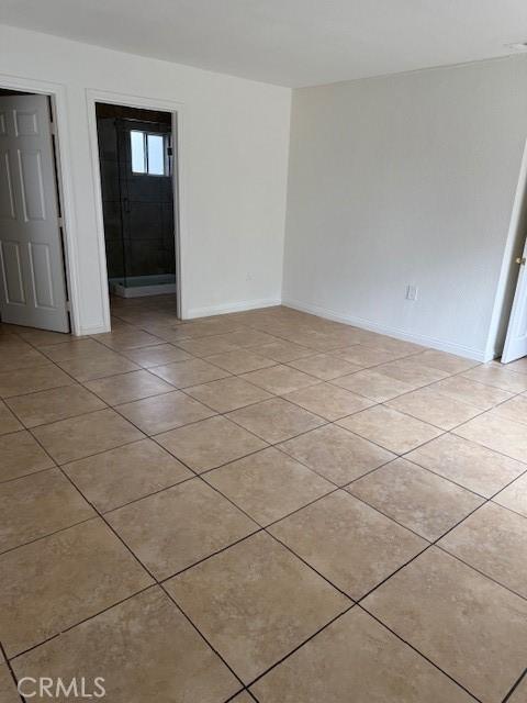 unfurnished room with light tile patterned floors and baseboards