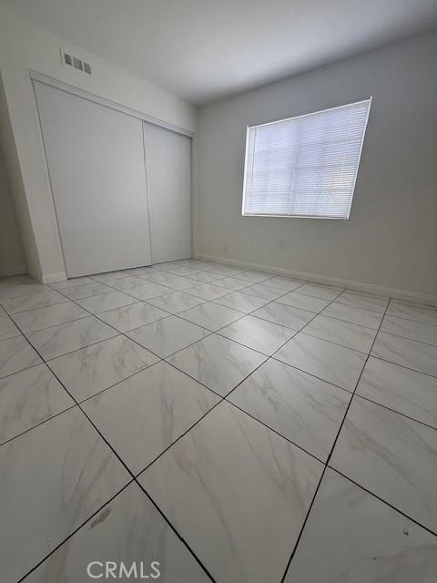 unfurnished bedroom with visible vents, a closet, and baseboards