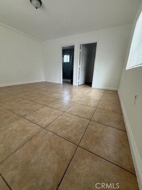 empty room with a wealth of natural light, baseboards, and light tile patterned flooring