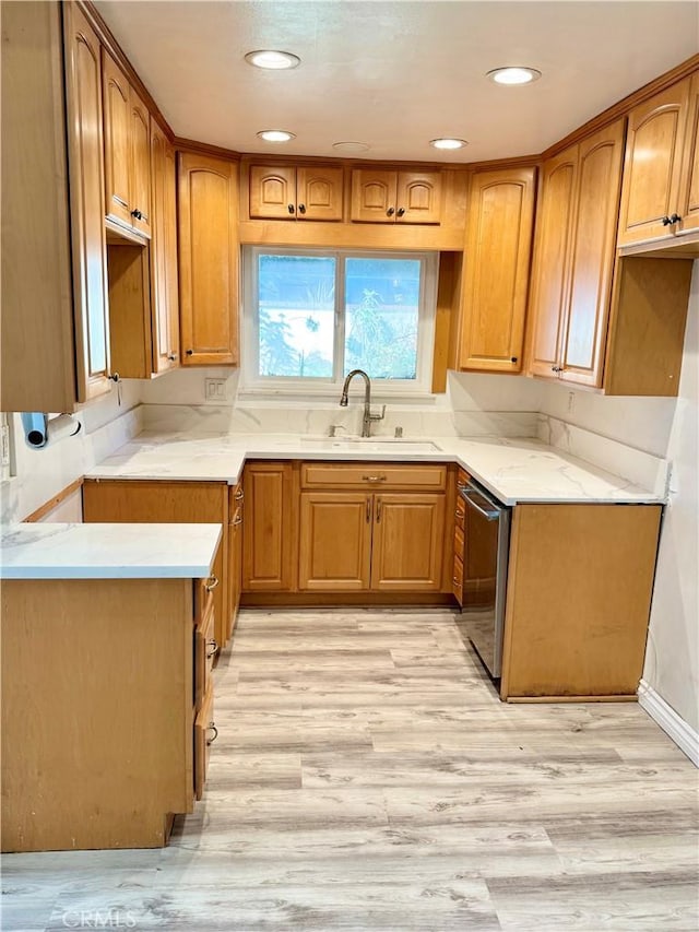 kitchen with a sink, light wood-type flooring, brown cabinets, and stainless steel dishwasher