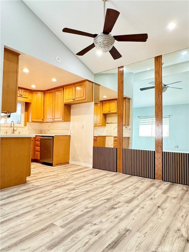 kitchen with brown cabinetry, a ceiling fan, vaulted ceiling, dishwasher, and light wood-type flooring