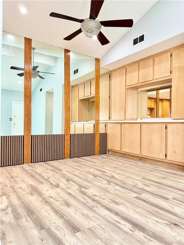 unfurnished room with vaulted ceiling, a ceiling fan, visible vents, and light wood finished floors