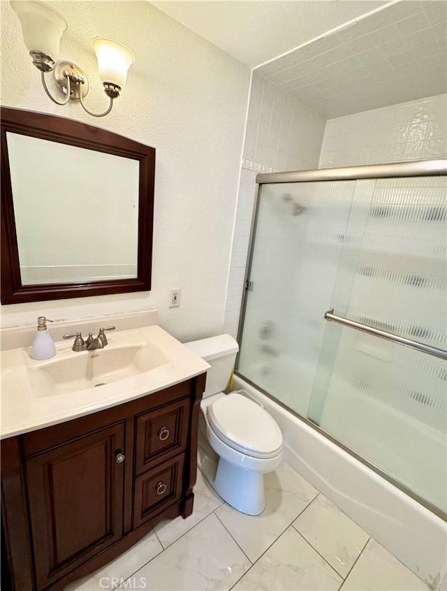 bathroom featuring enclosed tub / shower combo, toilet, and vanity