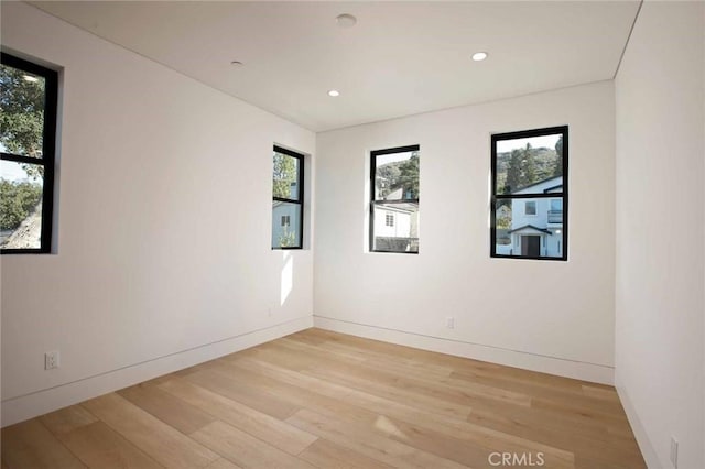 unfurnished room with a healthy amount of sunlight, light wood-type flooring, and baseboards