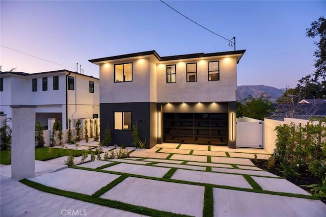 modern home with stucco siding, driveway, a gate, fence, and a garage