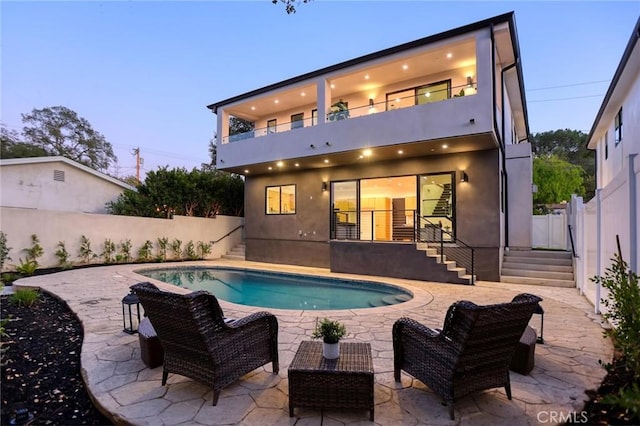 back of house with stucco siding, an outdoor hangout area, a fenced backyard, a balcony, and a patio