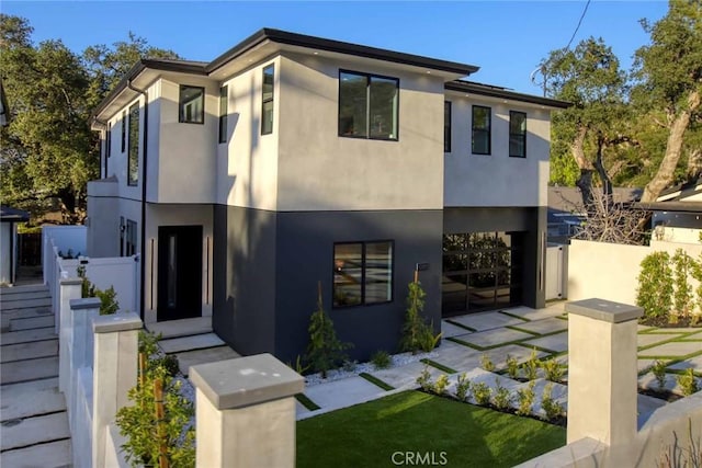 contemporary home with fence and stucco siding