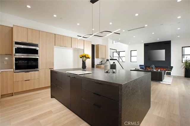 kitchen featuring light brown cabinetry, stainless steel double oven, light wood finished floors, and modern cabinets