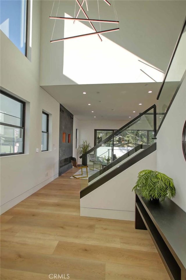 interior space with recessed lighting, wood finished floors, and a towering ceiling