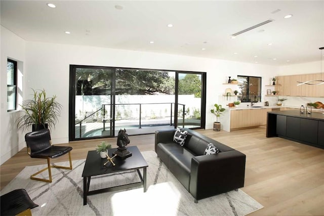 living area with recessed lighting, visible vents, and light wood finished floors