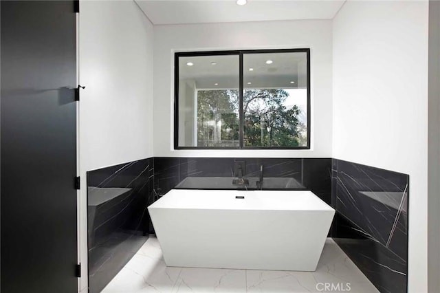 bathroom featuring a wainscoted wall, recessed lighting, marble finish floor, and a freestanding bath